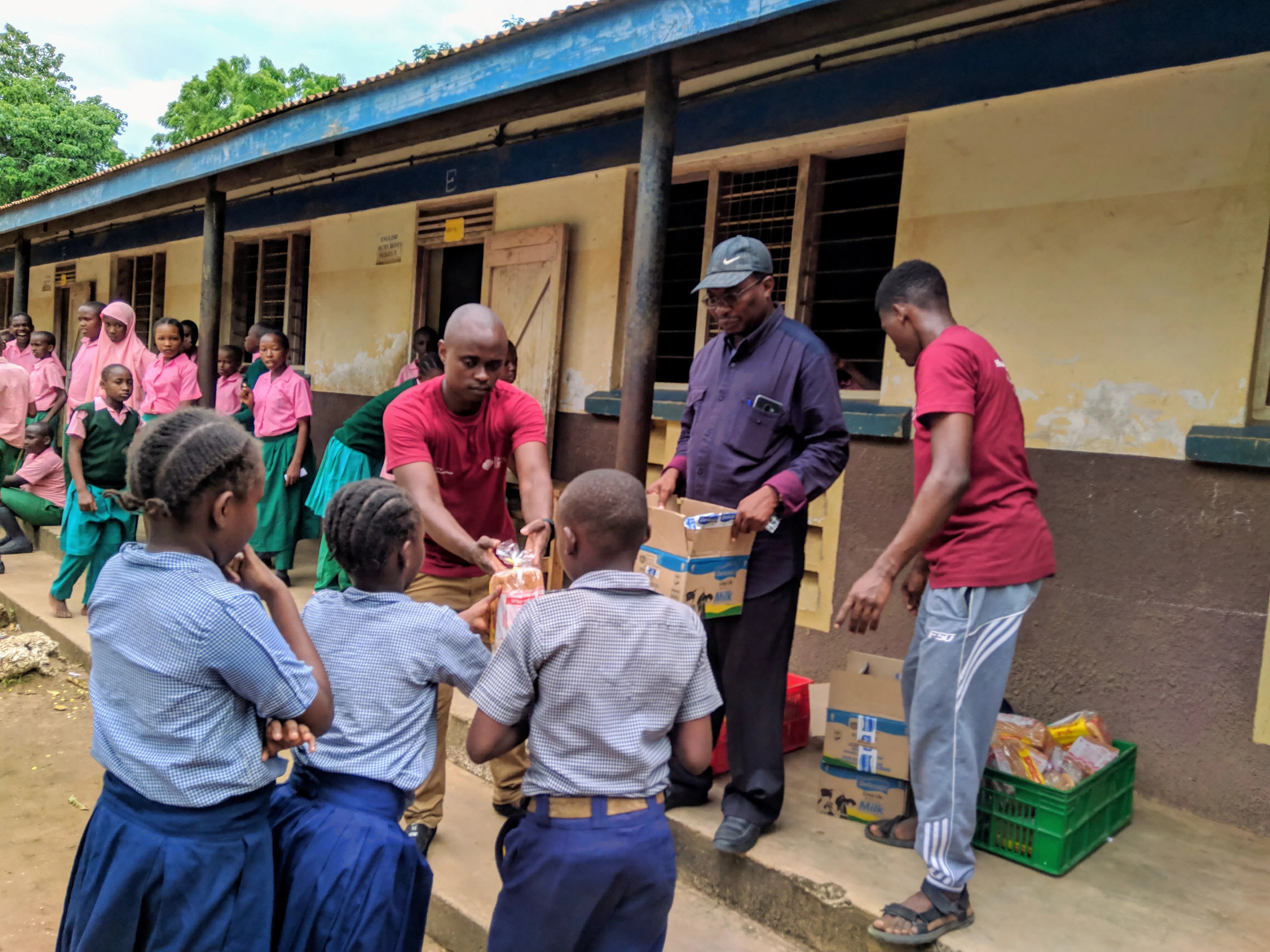 A group of boys and girls and their teachers lining up outside for an event