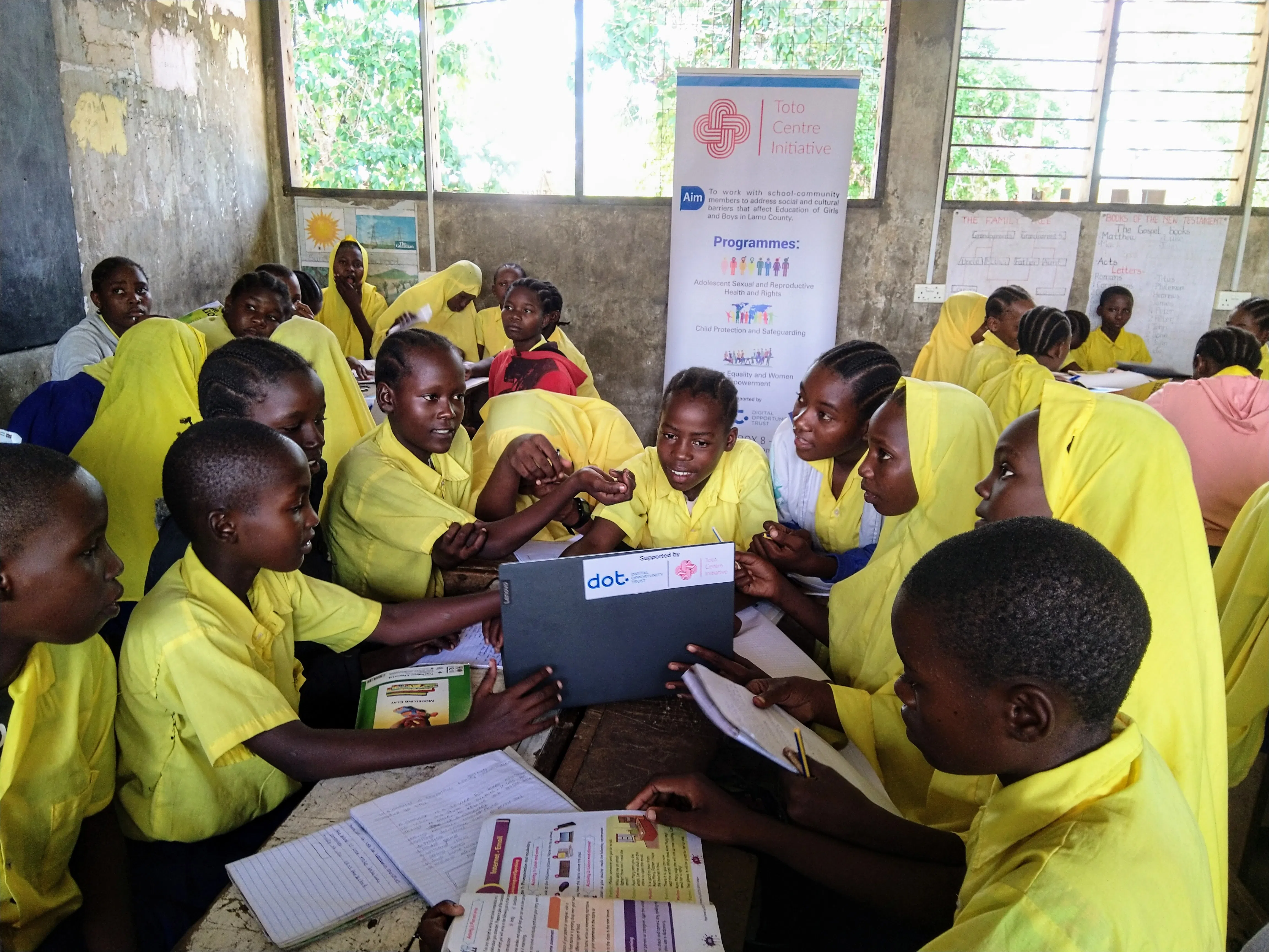 A group of boys and girls sitting at a table and learning how to use a computer 