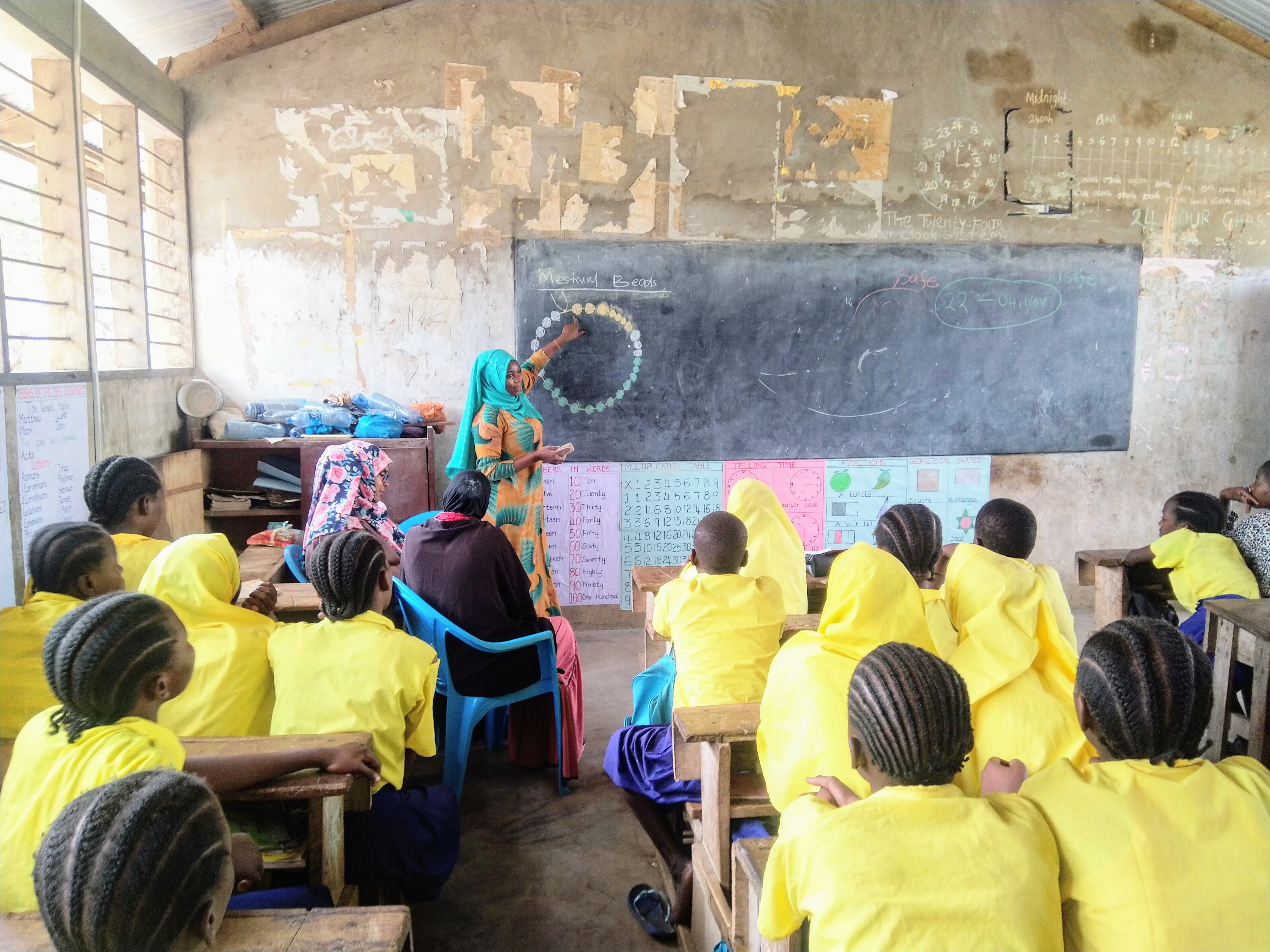 A teacher in the classroom explaining a group of girls of a menstrual bracelet works