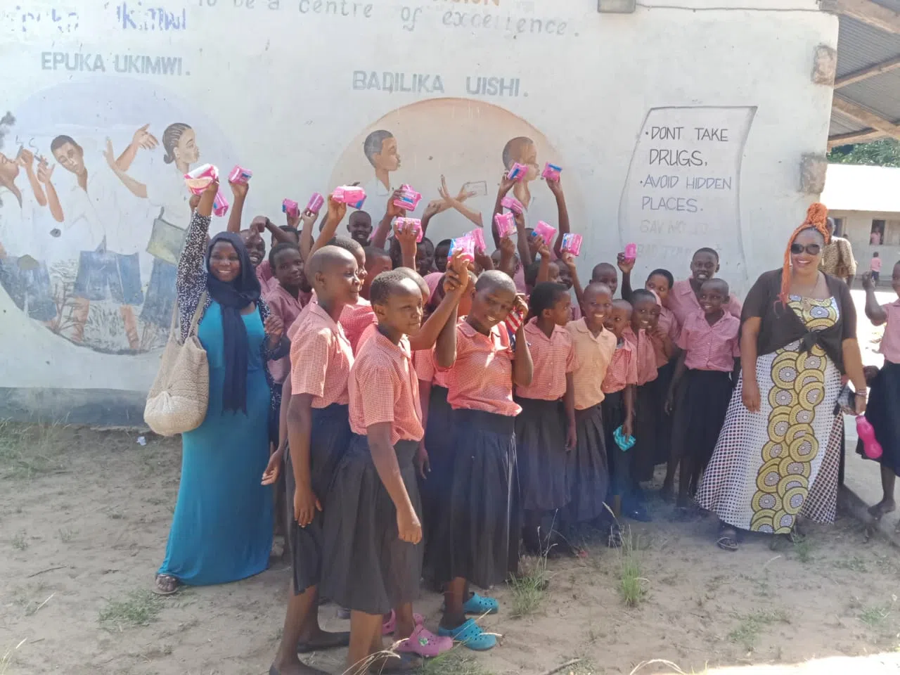 A group of kenyan girls outside holding pads